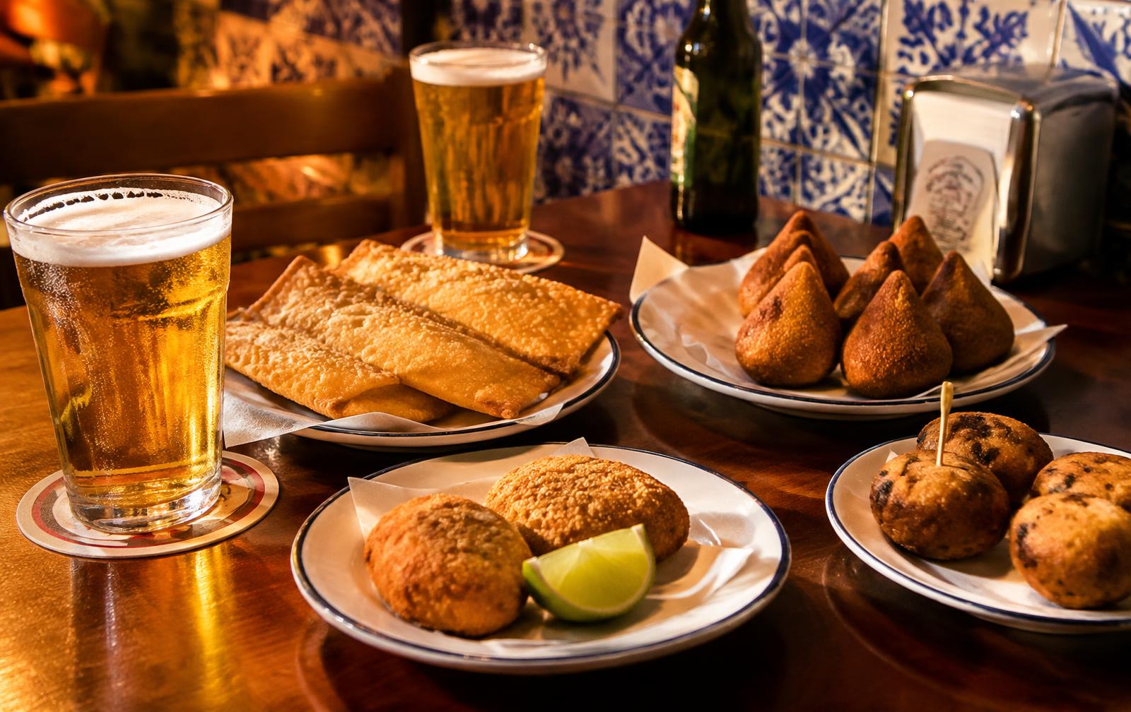 Mesa com cerveja, pastéis e coxinhas no Bar Santinhos